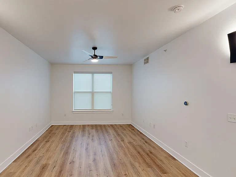 Spacious apartment bedroom with wood-style flooring.