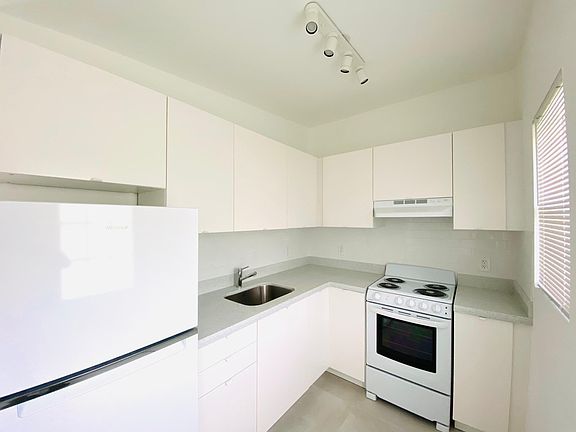 Kitchen with stone countertops, new high efficiency whirlpool refrigerator and hotpoint range. Led lights, and stainless steel sink.