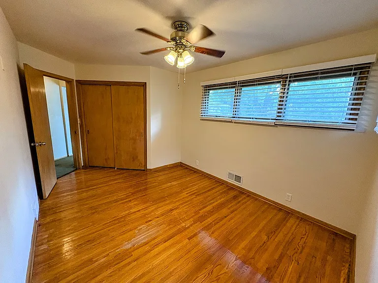 Relaxing primary bedroom. Hardwood floors. Ceiling fan. Raised awning-style windows provide privacy and invite in the sunshine.