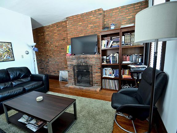 Living Room has High Ceilings, exposed Brick Wall and Wood Burning Fireplace. Original Natural Wood Floors.