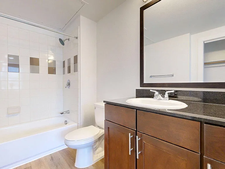 Apartment Bathroom with soaking tub, vanity mirror and wood-style floor.