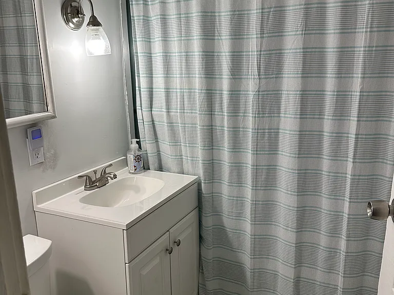 Bathroom with tile floor and tub/shower. Built in shelving on the south wall.