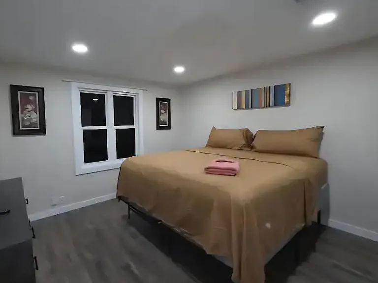 Spacious bedroom with a comfortable bed, overhead recessed lighting, and a window for ventilation and natural light.