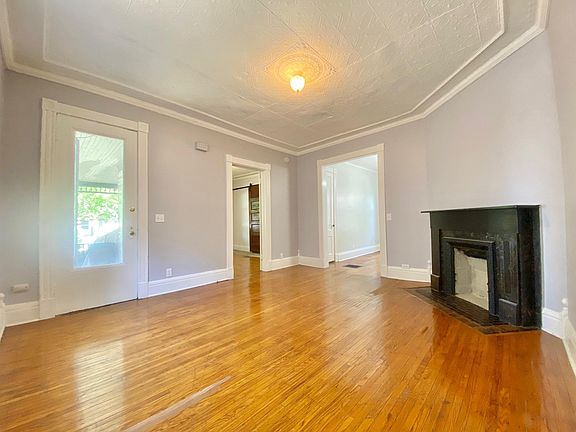 Living room with fireplace leading into the kitchen on the right and bedroom door on the center left