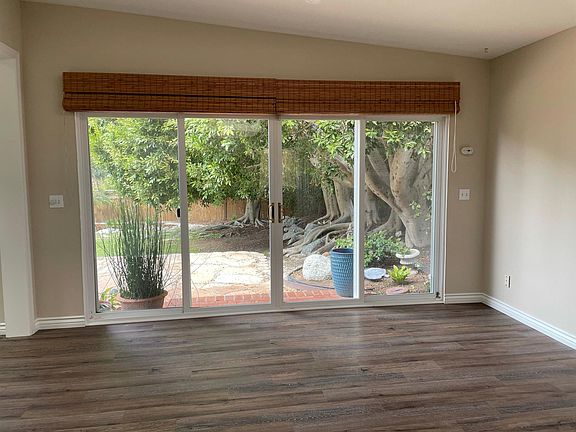 Large Windows overlook lush patio and garden