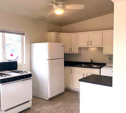 KITCHEN WITH CEILING FAN, VAULTED CEILING AND NEW FLOOR. CABINET IN FORGROUND IS MOBILE & CAN BE MOVED TO THE CORNER OF KITCHEN FOR A PREFERANCE.