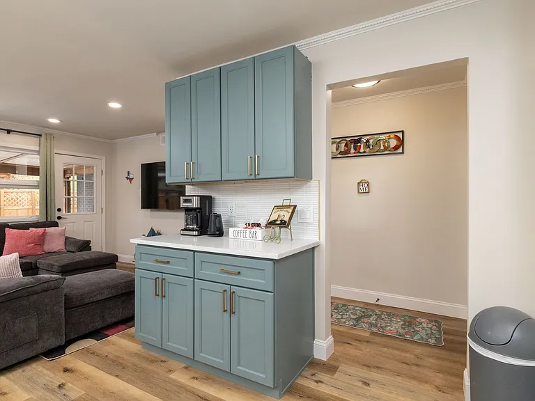 A fully stocked coffee bar with drip maker, instant coffee, grounds, tea kettle, a variety of teas, and an air fryer. Stylish teal cabinets and comfy seating make this space perfect for relaxing and recharging.