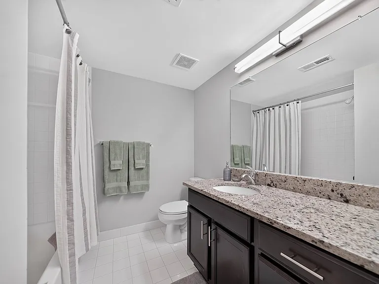 Modern bathroom with large vanity mirror and tub/shower at Lakeside Village Apartments in Clinton Township, MI
