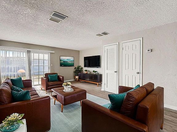 Inviting living room with plush brown leather sofas, vibrant teal cushions, and abundant natural light from large sliding doors.