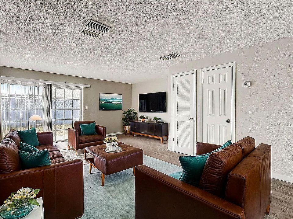 Inviting living room with plush brown leather sofas, vibrant teal cushions, and abundant natural light from large sliding doors.