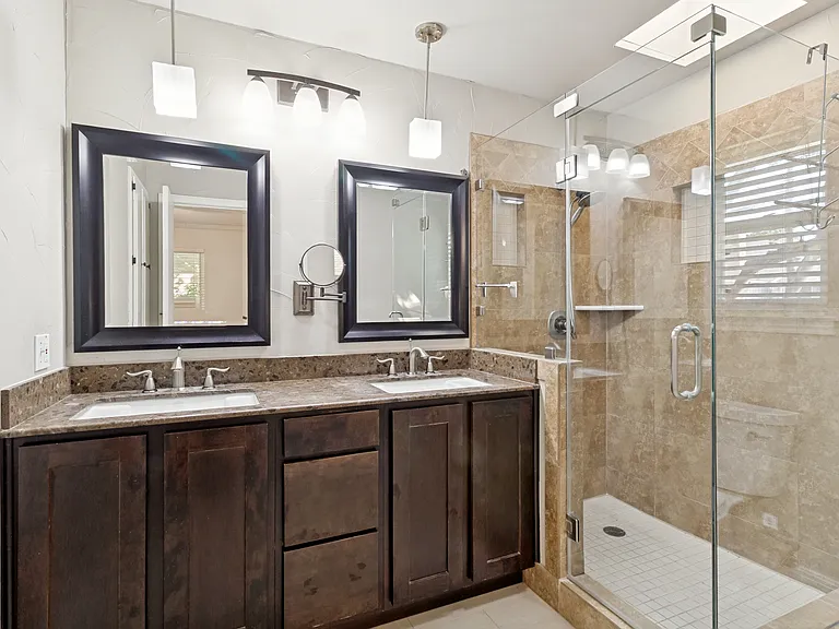 Start your mornings out right with this beautifully Italian-inspired stone tile, frameless shower with skylight above, the tall dual-sinks vanity and extra storage with the built-in linen closet (not pictured).