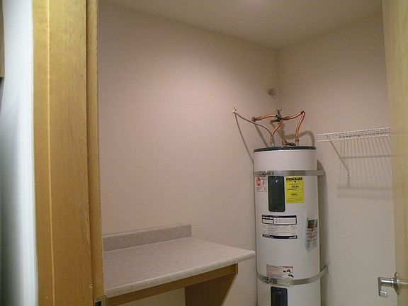 Laundry room has space for washer/dryer & houses water heater, table & shelf