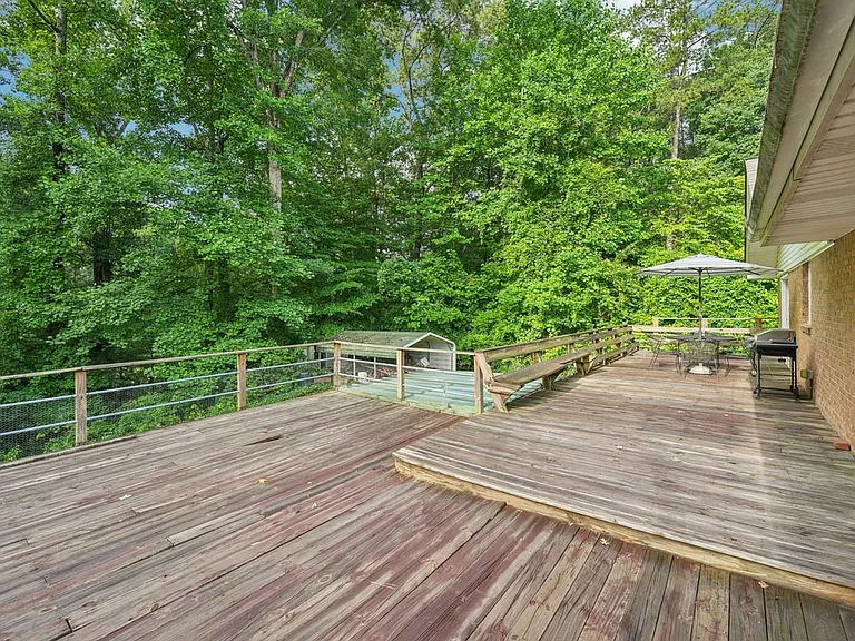 Wrapped in greenery and softened by natural light, this outdoor deck feels like a hidden garden perch designed for laughter, leisure, and peaceful moments beneath the trees.