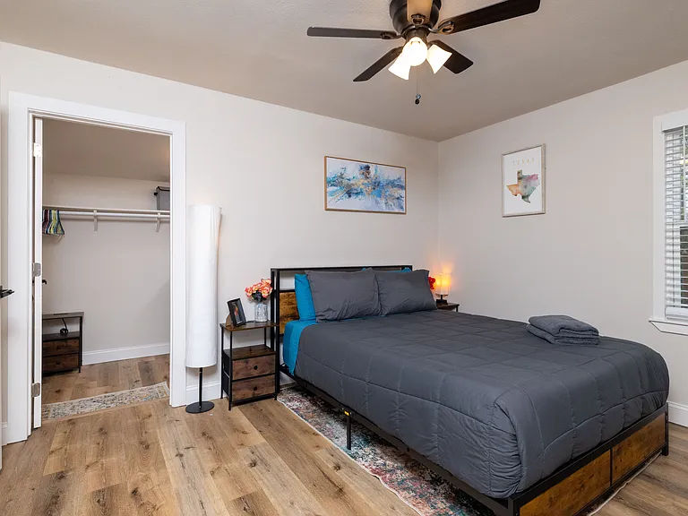 Spacious primary bedroom with a comfy queen bed, walk-in closet with extra storage, attached bathroom, and a dedicated workspace/vanity. Peaceful, bright, and perfect for relaxing or getting work done.