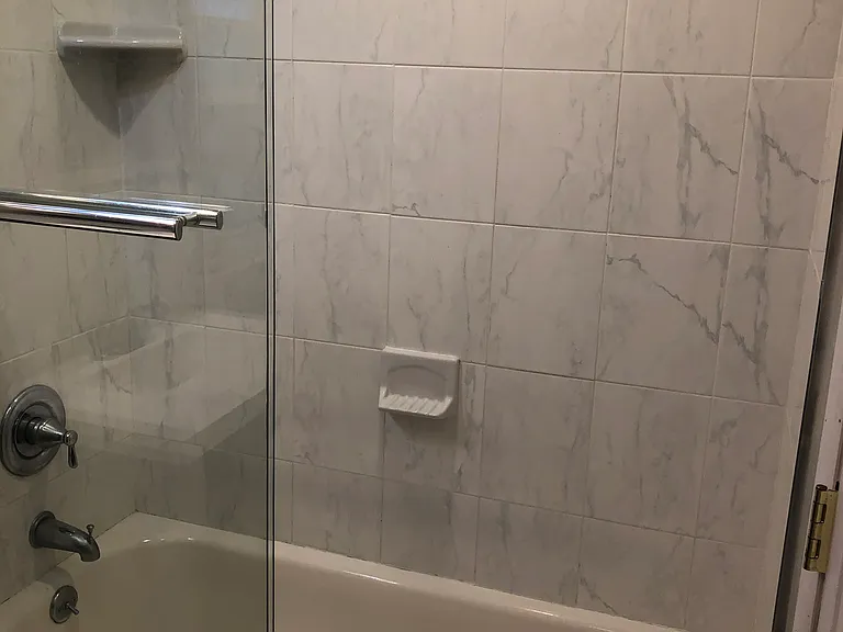 newly renovated bathroom with marble tile and sliding galss shower door