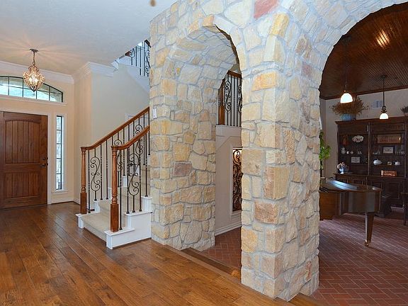 Step down through the stone arches into the formal living room with custom wood ceiling and tiled fl