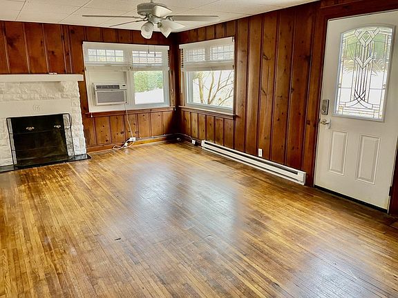 Living room with large double sized windows, hardwood blinds, non-working fireplace