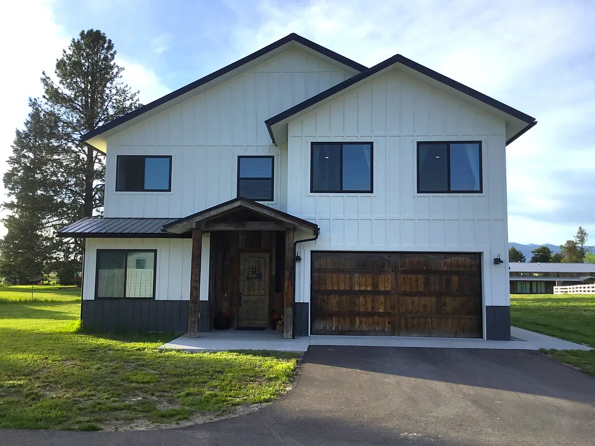 Beautifully designed two-story Montana retreat featuring a stunning rustic entry door, spacious two-car garage, and oversized driveway, all surrounded by peaceful mountain scenery and the timeless warmth of Montana living. - 216 Cowboy Dr