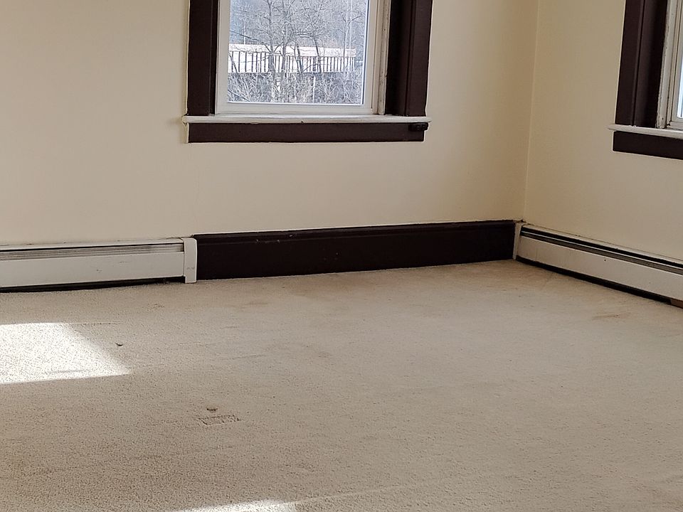 carpeted large bedroom on corner of building which has three large windows