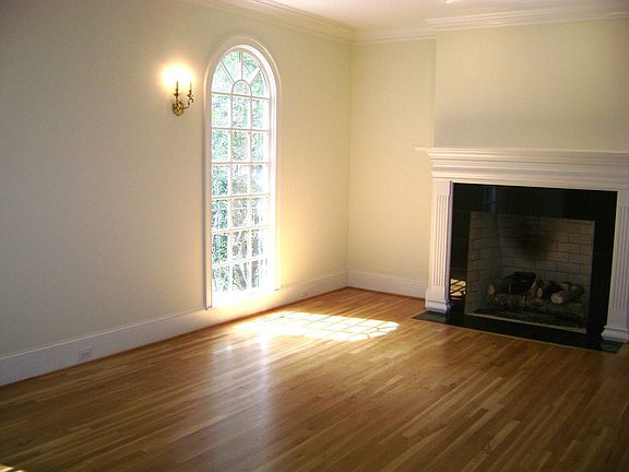 LARGE LIVING ROOM HAS HARDWOODS AND OVERSIZED GRANITE TILED FIREPLACE.