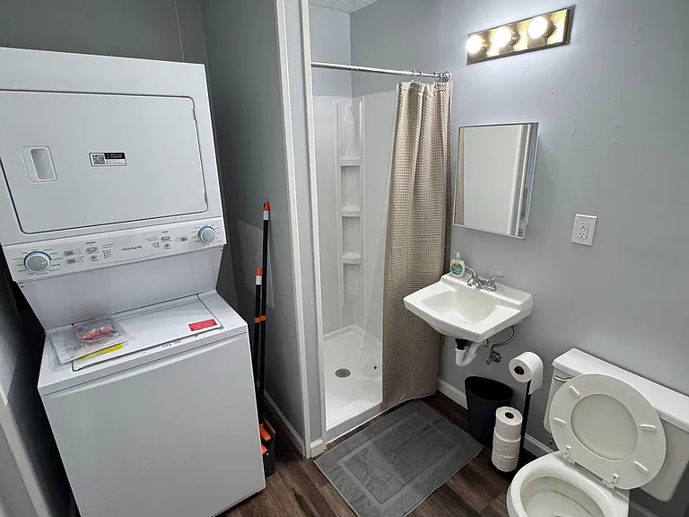 Full bathroom with walk-in shower and vanity, plus convenient in-room stacked washer/dryer for easy laundry access.