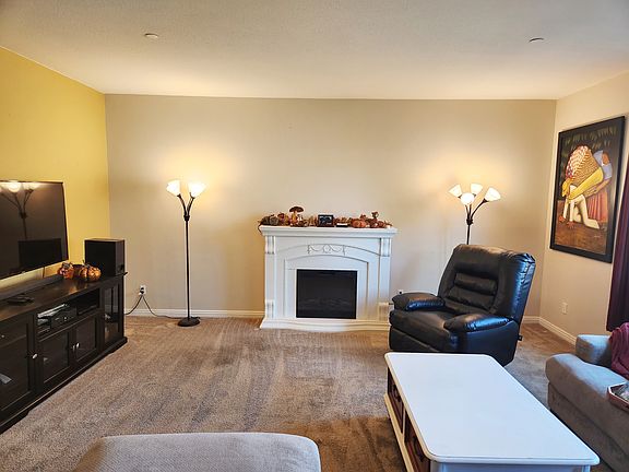 Relaxing by the electric fire place is great for all seasons. Recliner by the fireplace. Sectional couch around coffee table full of games. Intertainment center. Painting on wall tops it all off.