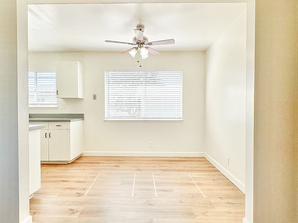 an empty living room with a ceiling fan and a kitchen