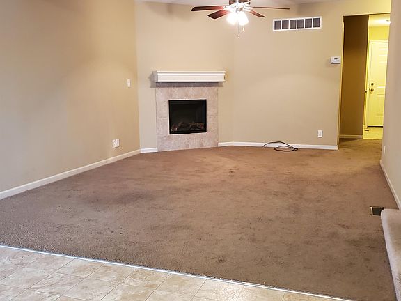 Living room with an electric fireplace and ceiling fan.