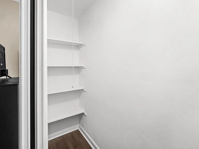 Extra storage nook with built-in shelving provides convenient space for pantry items, linens, or supplies.