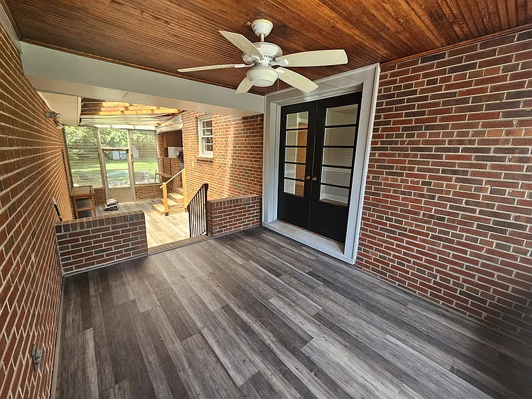 Enclosed porch with ceiling fan and new LVP flooring.