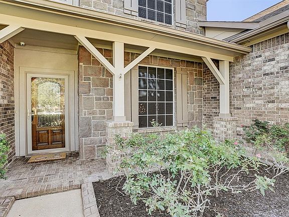 Inviting covered front porch with storm door prior to opening the beautiful etched glass wood door.