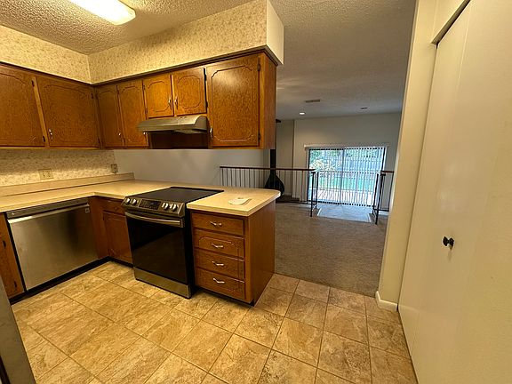 Kitchen with lots of cabinets, looking over the dining area (or sitting or office), looking into step down living room, then out to private deck.