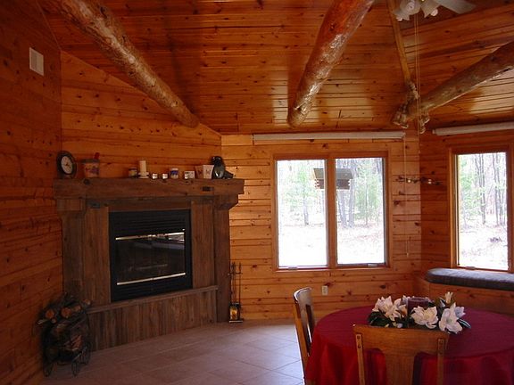 Wood burning heatalator in great room, shows log beams at ceilimg.