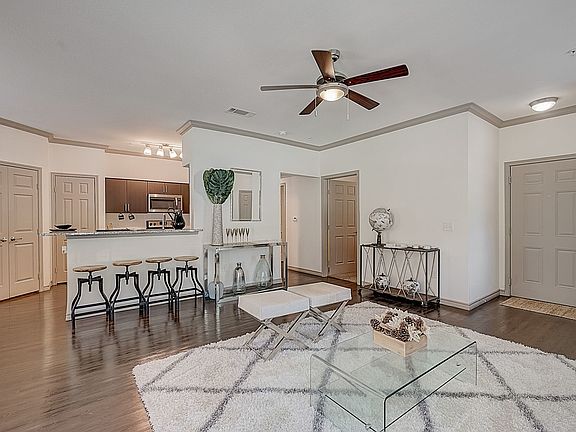 Open kitchen with granite countertops, stainless steel appliances and dark cabinets overlooking separate dining area