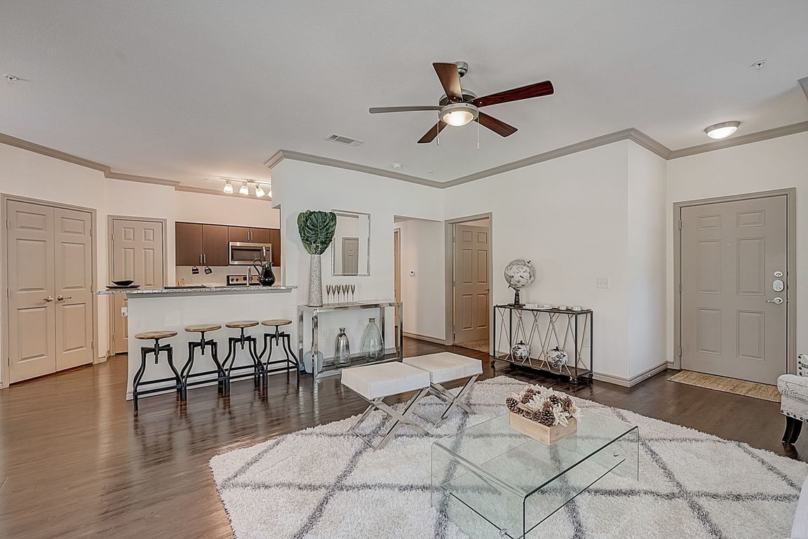 Open kitchen with granite countertops, stainless steel appliances and dark cabinets overlooking separate dining area