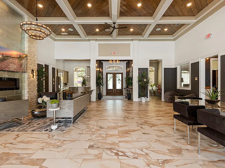 Elegant and spacious lobby featuring luxurious marble flooring, stylish seating areas, and vibrant indoor plants under a stunning wooden ceiling with decorative lighting.