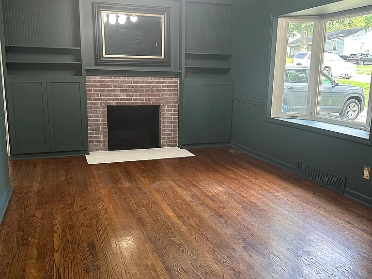 Living room featuring hardwood floors, fireplace (nonfunctional), and built-in closed and open storage