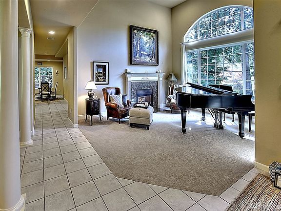 Formal living room features two-sided gas fireplace and large window with view of the front yard. 