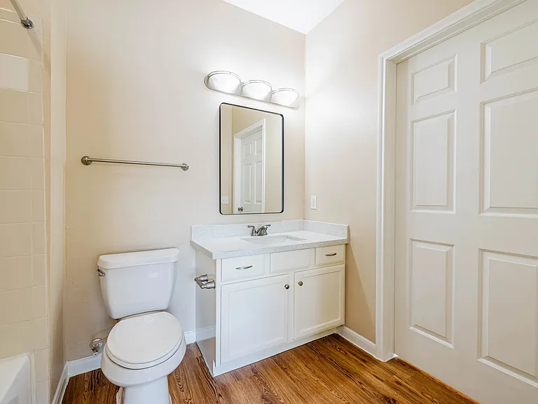 Bright and modern bathroom featuring elegant cabinetry, a large mirror, and sleek fixtures on wood-style flooring. Bright and modern bathroom featuring elegant cabinetry, a large mirror, and sleek fixtures on wood-style flooring.