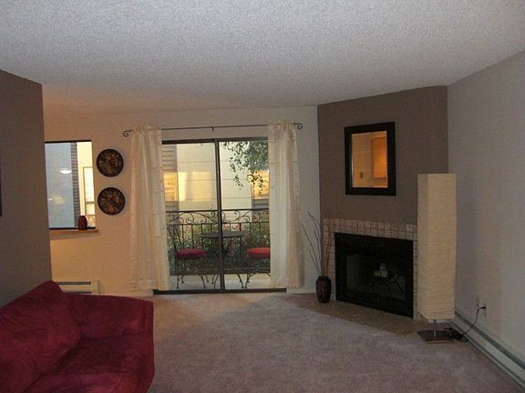 Spacious Living Room with Cozy Corner-Set Wood-Burning Fireplace! Note the Sliders to Balcony.