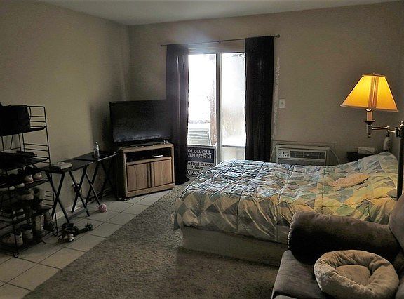 Sliding glass door off of living room opens onto a little concrete patio