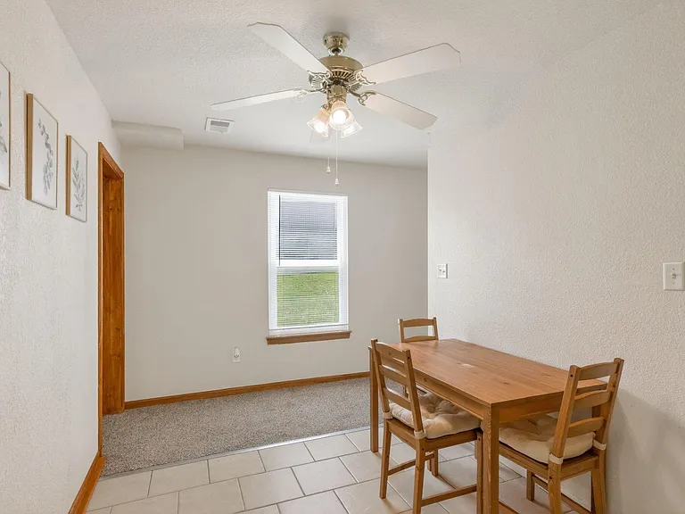 Dedicated dining area with a ceiling fan, tiled flooring, and a window for natural lightideal for everyday meals or work.