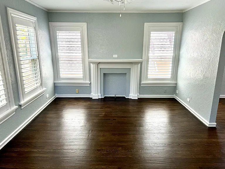 Dining room with feaux fireplace, beautiful hand scraped hard wood floors and plantation wood shutters.
