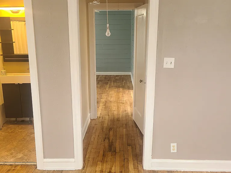 From bedroom, looking down hallway to living room. Bathroom to the left.