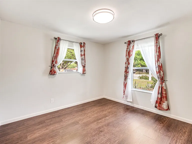 Room featuring wood-finish flooring, two windows, and a flush-mount ceiling light
