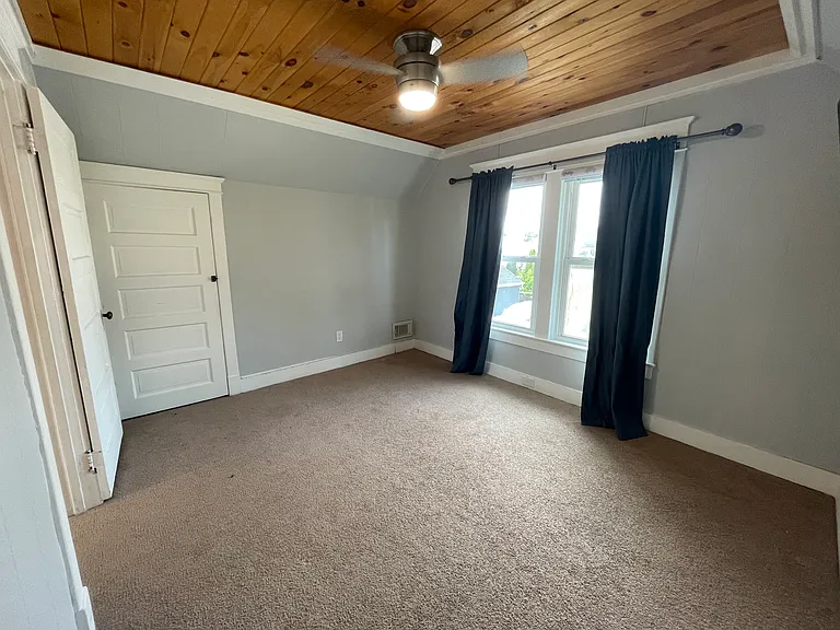 Upstairs bedroom with two closets and a cozy wood ceiling accent.