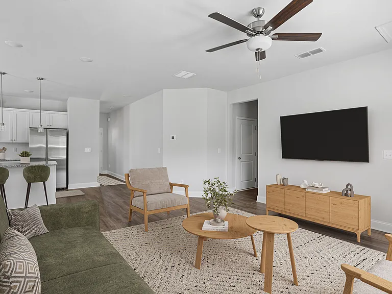 Spacious living room with a plush sectional, modern wood-accent chair, and sleek entertainment center