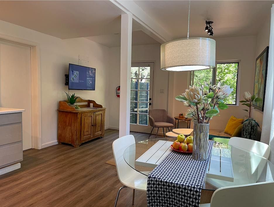 The view overlooking the lounge from the bedroom. The entry door and the garden are in the far side of the room. Door on left leads to the bathroom, which has a storage area and an access door to the laundry room, as well as another exit to the street, (t