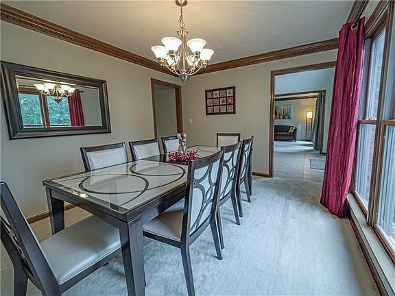 The formal dining room features large, bright windows, neutral decor and crown molding.