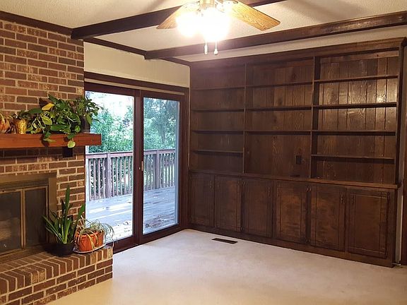 This cozy room has a fireplace, ceiling fan, and built-in storage, with a French door to a large back deck with a peaceful view of the yard.